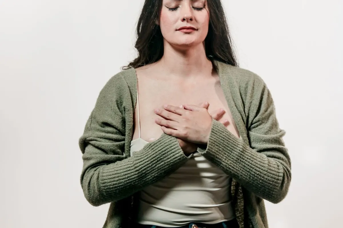 Femme assise en tailleur, les mains posées sur la poitrine, qui respire lentement