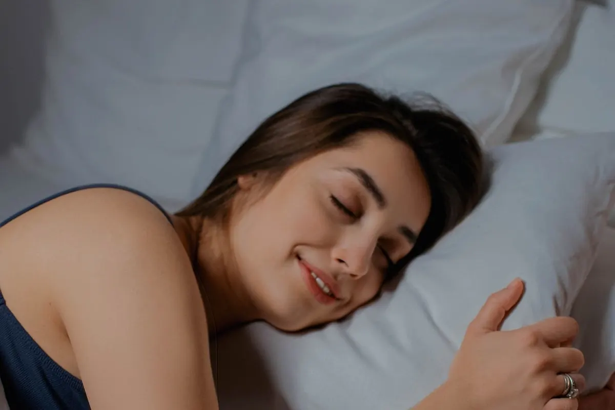 Femme qui dort paisiblement, les yeux fermés, dans un lit aux draps blancs